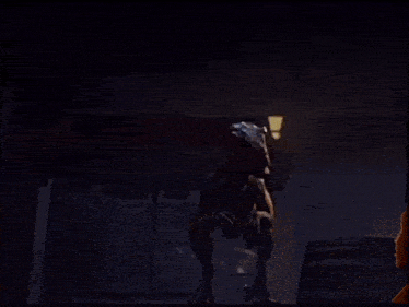 a dinosaur standing in a dark room with a light shining on it