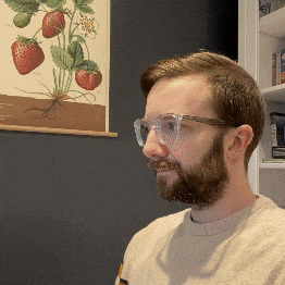 a man with glasses and a beard is standing in front of a strawberry poster