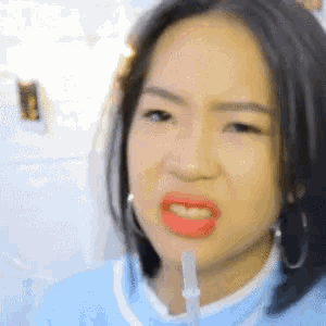 a close up of a woman making a funny face with a syringe in her mouth .