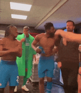 a group of men are dancing in a room and one of them is wearing a green jacket with the number 2 on it ..
