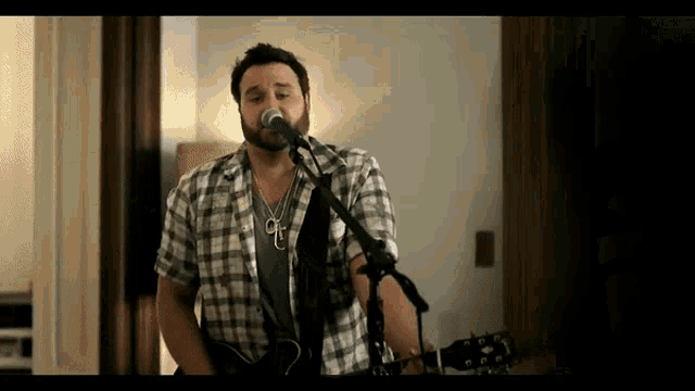 a man is singing into a microphone while holding a guitar