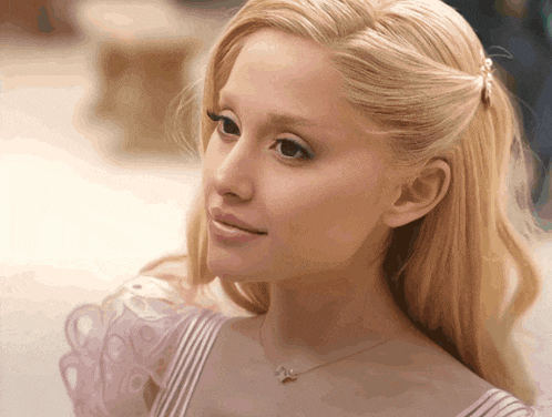 a close up of a woman 's face with blonde hair and a necklace with a butterfly on it