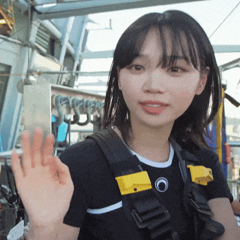 a girl wearing a black shirt and a yellow harness waves