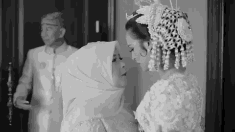 a bride and her mother are standing next to each other in a room .