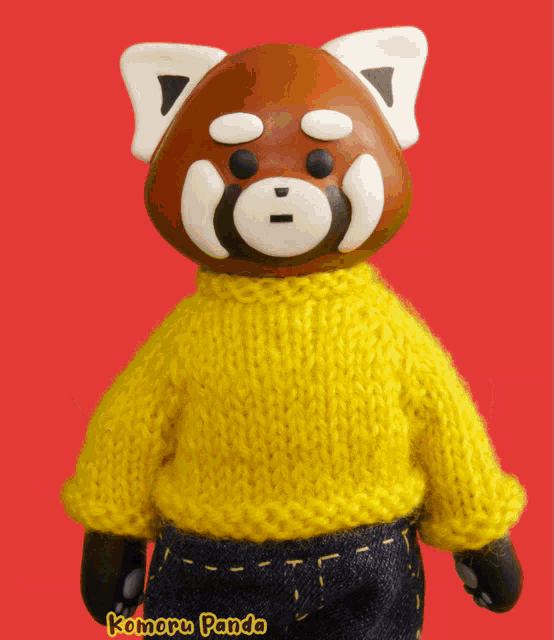 a red panda wearing a yellow sweater with komoru panda on the bottom