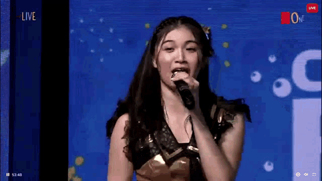 a young woman is singing into a microphone on a live stream .