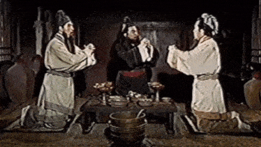 three men are kneeling in front of a table with a bucket on it