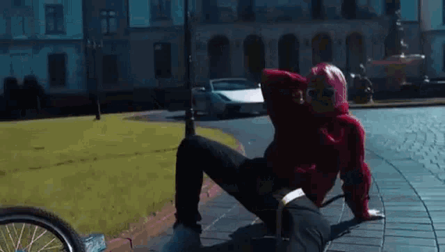 a woman in a red hoodie is sitting on the ground next to a bicycle .