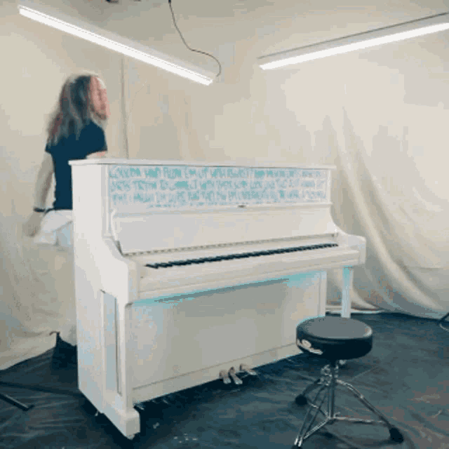 a man playing a white piano with words written on it that start with the letter a