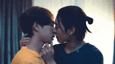 two young men are kissing and one has a cross on his neck