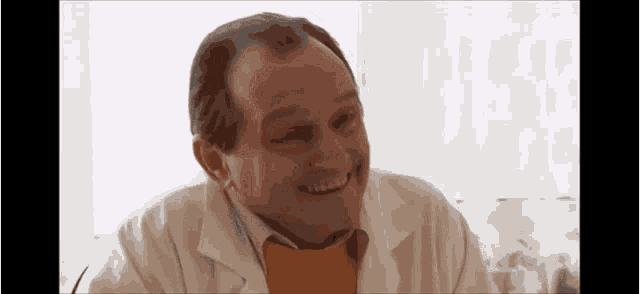a man in a lab coat is smiling and wearing an orange shirt