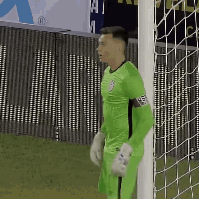 a soccer player wearing a green jersey with the word us on the sleeve