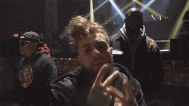 a man making a peace sign with his fingers in front of an exit sign