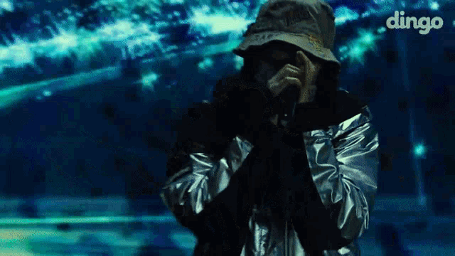 a man singing into a microphone with dingo written on the bottom right