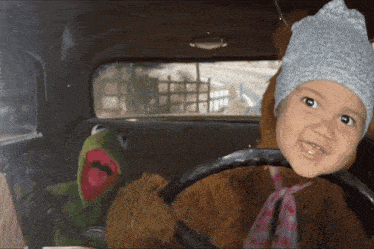 a little girl is sitting in a car with a kermit the frog stuffed animal