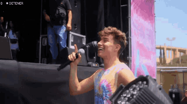 a man singing into a microphone with the word detener on the bottom left