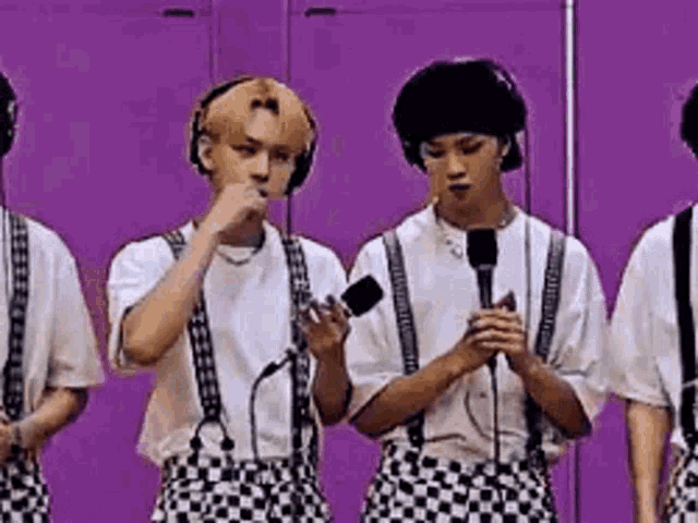 a group of young men wearing suspenders and headphones are standing next to each other holding microphones .