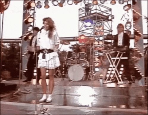 a woman is singing on stage in front of a band