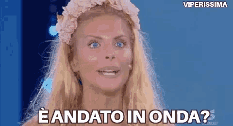 a woman with blonde hair and blue eyes is wearing a flower crown and says eandato in onda ?