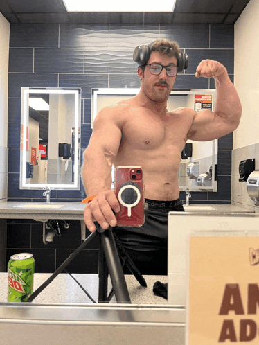 a man taking a selfie in a bathroom with a mountain dew can on the counter