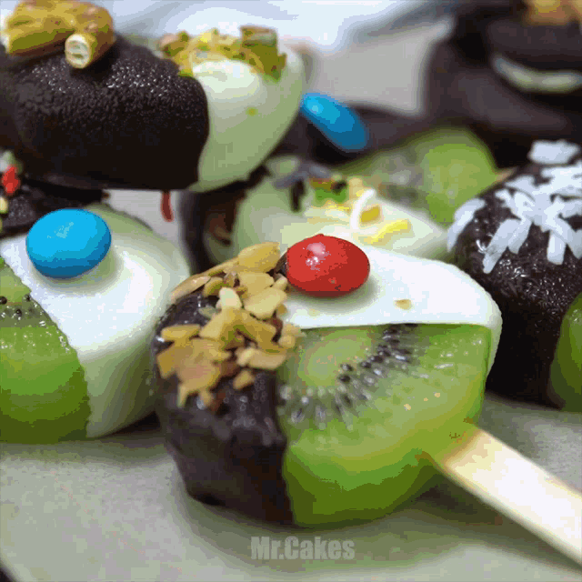 a close up of a kiwi covered in chocolate with the words mr.cakes below