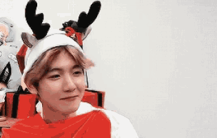 a young man wearing a santa hat and reindeer antlers is making a funny face .