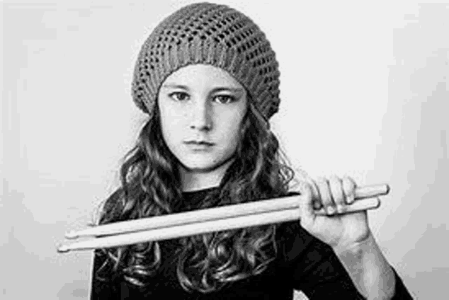 a black and white photo of a young girl holding drumsticks .