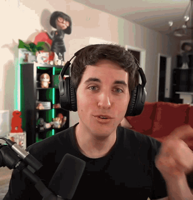a man wearing headphones stands in front of a microphone in a living room