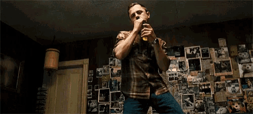 a man is singing into a microphone in front of a wall with pictures on it