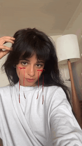 a woman in a white shirt has red ribbons coming out of her eyes