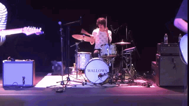 a man playing drums with the word wallows on the drum