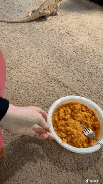 a person is holding a bowl of food with a fork in it