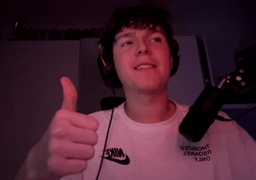 a man wearing headphones and a white nike shirt is giving a thumbs up