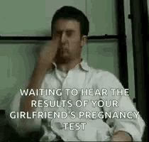 a man in a white shirt is covering his nose while waiting to hear the results of his girlfriend 's pregnancy test .