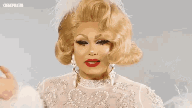 a woman with blonde hair and red lips is wearing feathers