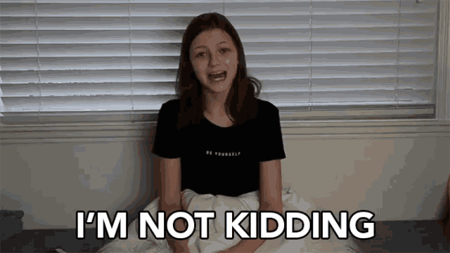 a girl is sitting on a bed with the words i 'm not kidding above her