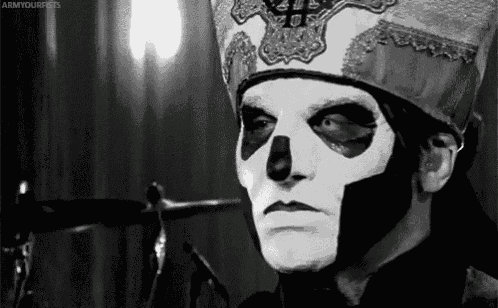 a black and white photo of a man with a skull face paint and a hat .