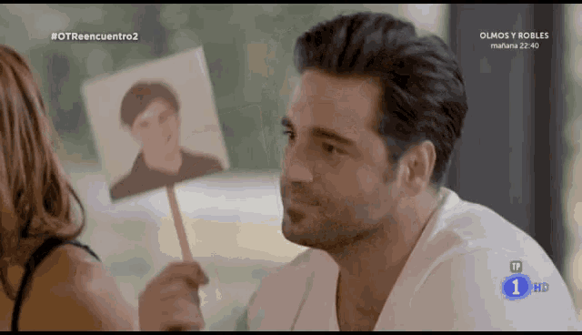 a man holds a picture of a man on a stick in front of a screen that says # otroencuentro2