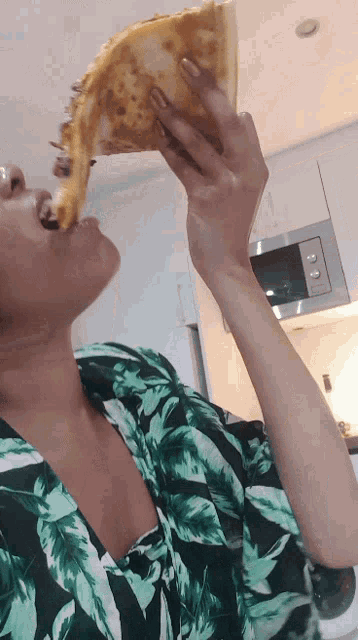 a woman is eating a slice of pizza with her mouth