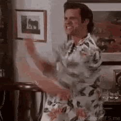 a man in a floral shirt is dancing in a living room in front of a picture .