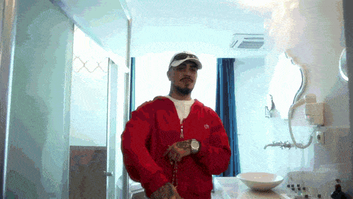 a man in a red jacket stands in a bathroom with a sink