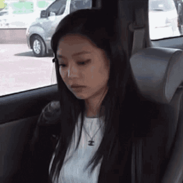 a young woman is sitting in the back seat of a car looking out the window .