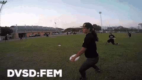 a woman throws a frisbee in a field with dvsd fem written on the bottom right
