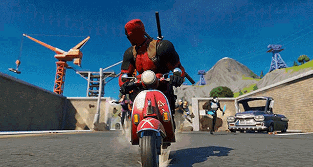 a man in a deadpool costume rides a red and white scooter