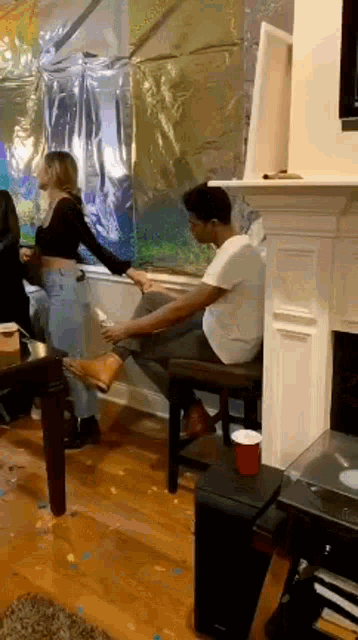 a man is sitting on a chair in a living room while a woman holds his foot .