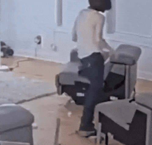 a man is standing on a chair in a living room