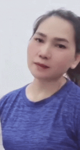 a woman in a blue shirt is making a funny face and looking at the camera .
