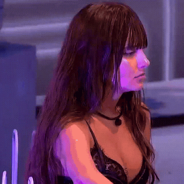 a woman with long hair is wearing a black bra and a purple background