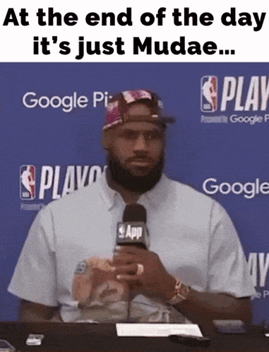 a man holding a microphone with the words at the end of the day it 's just mudae on the bottom