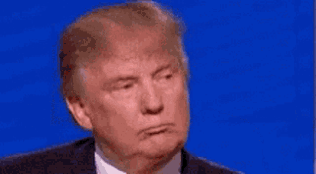 donald trump is covering his ear with his hand while talking on a blue background .